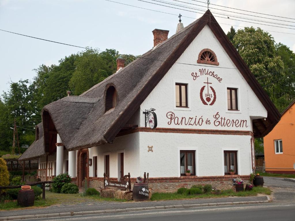 a white building with a thatched roof at St.Michael Panzió Lovaspark in Vasszentmihály