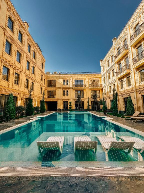 a large swimming pool in a building with two chairs at Meridian Plaza by Reikartz in Samarkand
