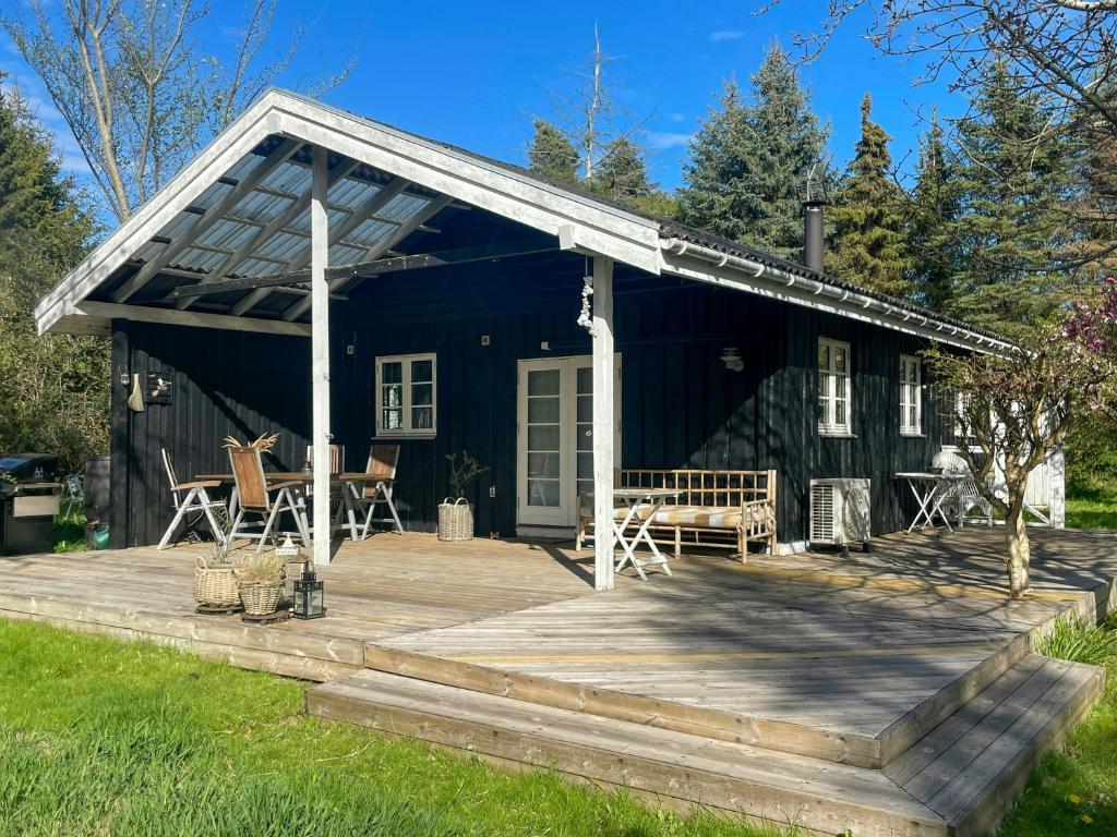 a black cottage with a porch and a deck at Seaside Cabin With Ocean View In Odsherred in Nyrup