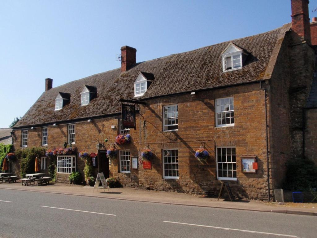 an old brick building on the side of the street at The George Inn in Lower Brailes