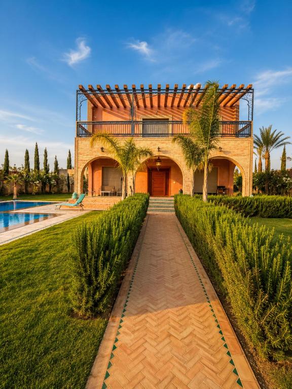 a house with a pathway leading to a pool at VILLA Les 3 Palmiers in Amezrou