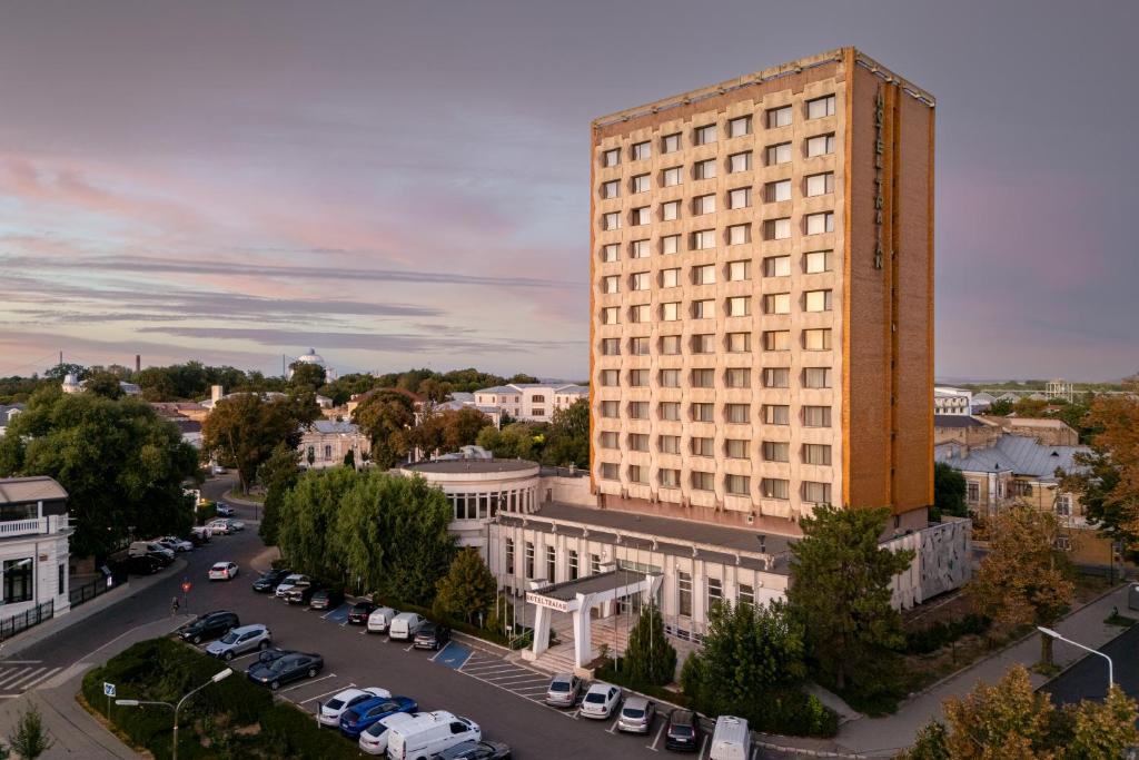 a tall building in a city with a parking lot at Hotel Traian in Brăila