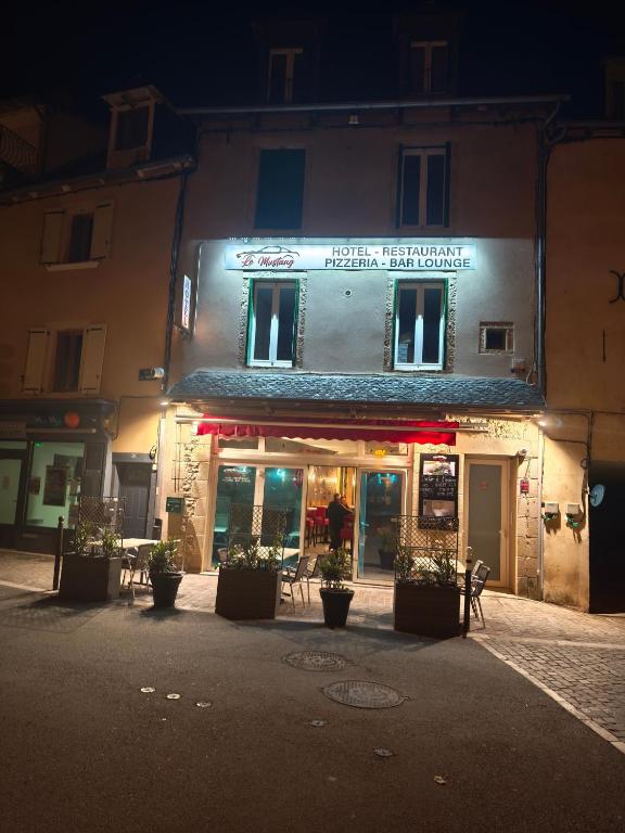 a building with a sign on it at night at Le MUSTANG in Saint-Geniez-dʼOlt