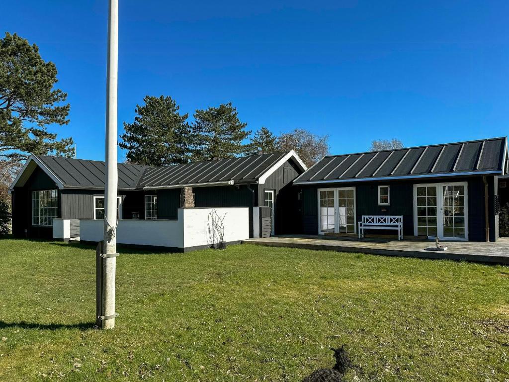 a black and white house with a pole in the yard at Beach House In Liseleje in Liseleje