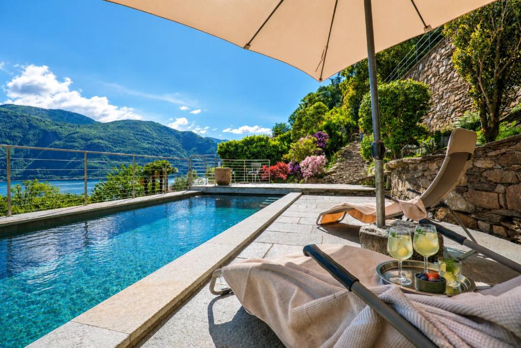a table with an umbrella next to a swimming pool at Villa Amore in Cannobio