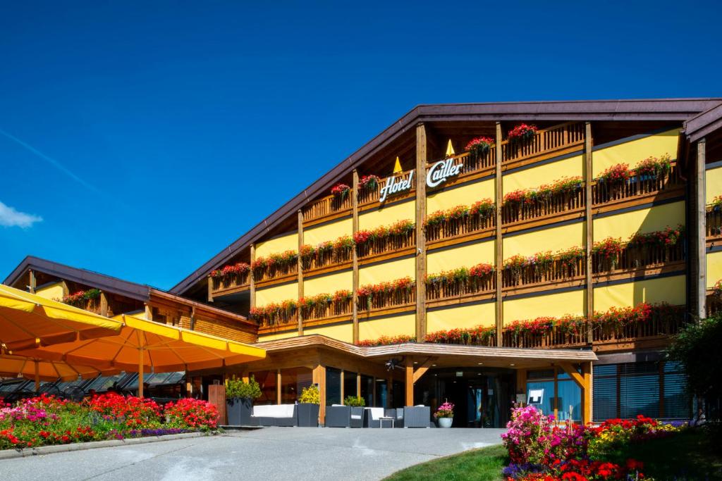 a large building with flowers in front of it at Hôtel Cailler & Bains de la Gruyère in Charmey