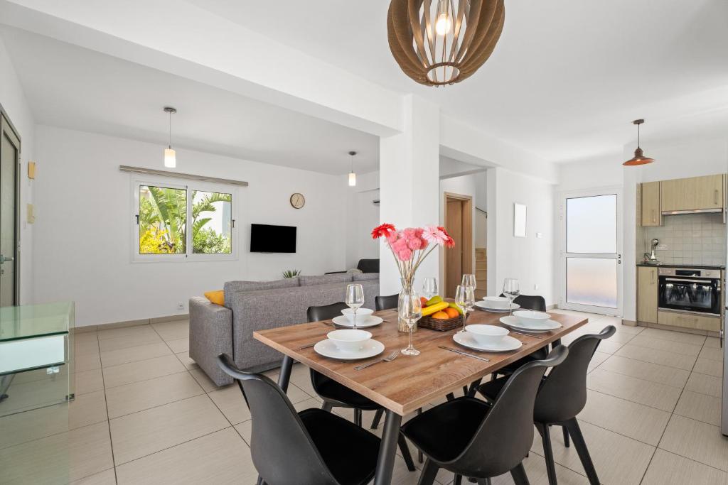 a dining room and living room with a table and chairs at Nissini Villas in Ayia Napa