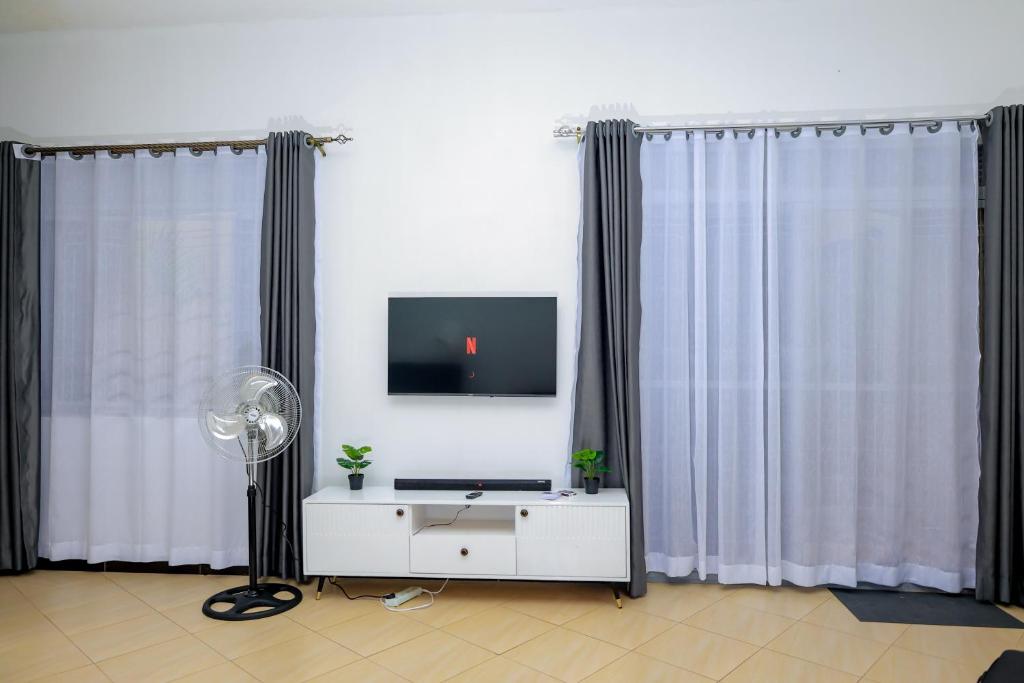 a living room with curtains and a tv and a table at The Comfort Den in Kampala