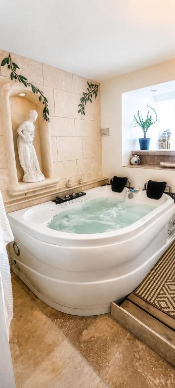 a large bath tub with a statue in a bathroom at Le secret de Santorin in Martigues