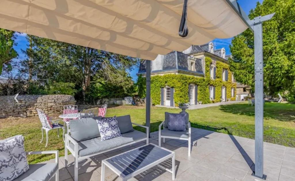 an outdoor patio with chairs and an umbrella at Manoir du Village in Irais