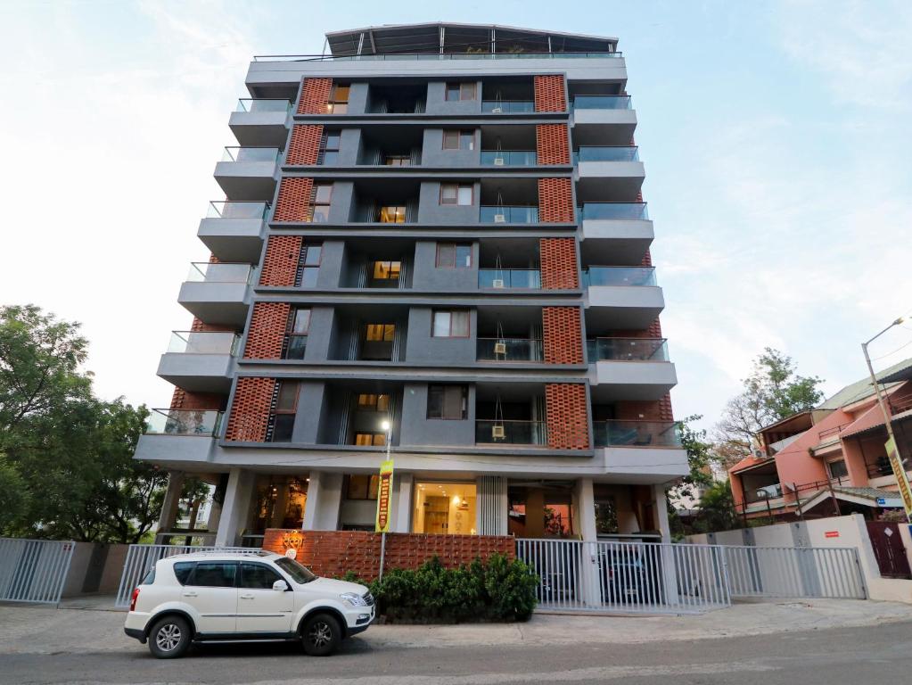a white car parked in front of a tall building at Hotel Tattva Suites NIBM, next to Corinthians Club in Pune