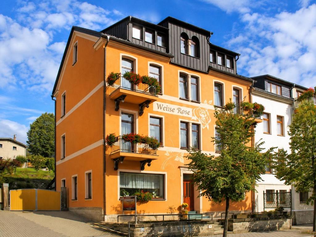 an orange building with flowers on the balconies at YFB Frühstückspension Weiße Rose I Zentral gelegen in Bad Elster