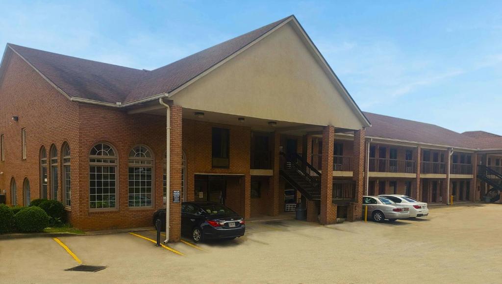 a large brick building with cars parked in a parking lot at Magnuson Hotel Marietta in Marietta