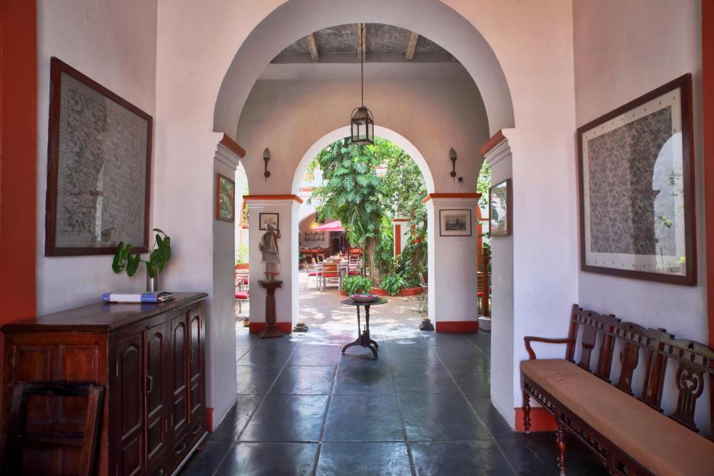 a hallway with an archway with a bench and a table at Dune de L'orient in Pondicherry