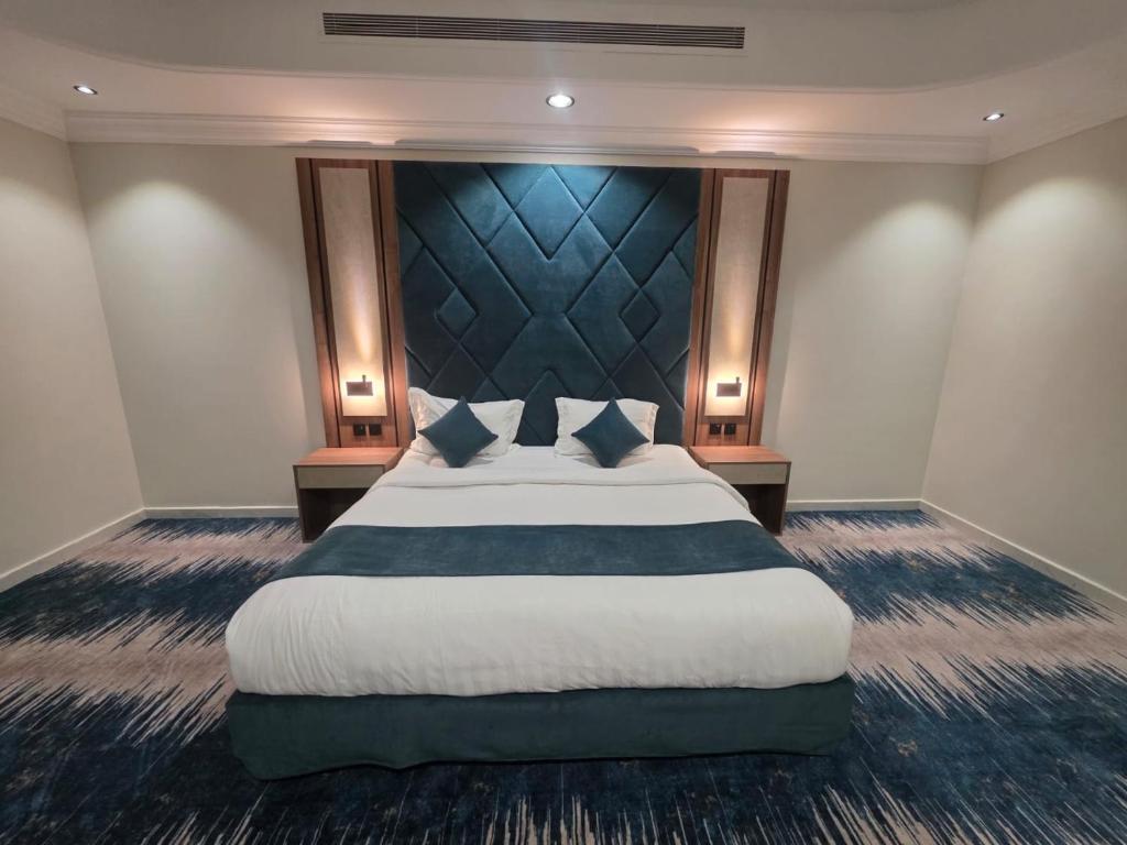 a bedroom with a large bed with a blue headboard at جلنار الشرق للشقق المخدومة in Jeddah