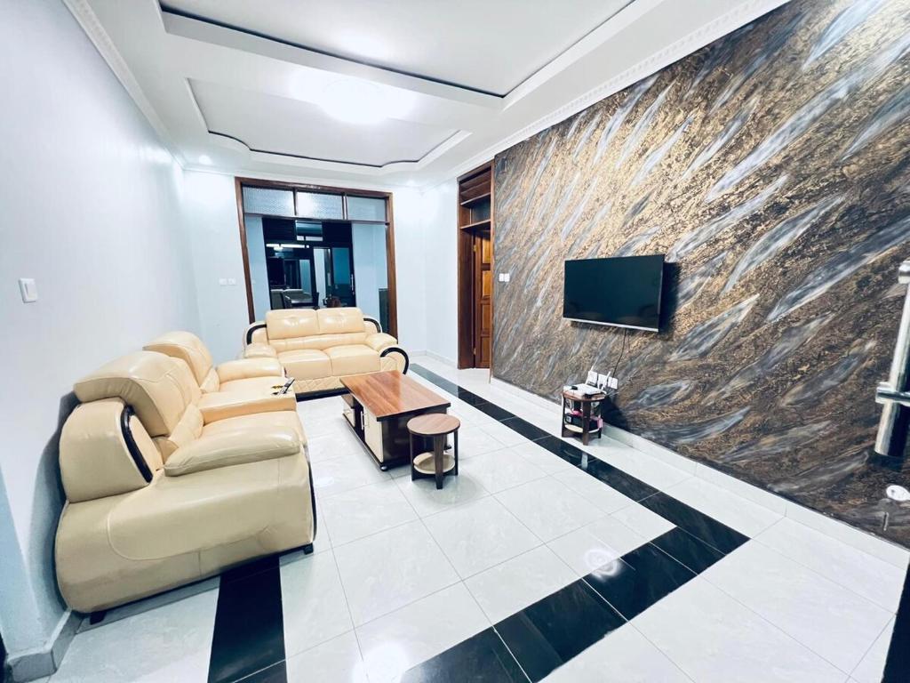 a living room with couches and a wall with a tv at The Gateway Luxury Apartment in Kigali