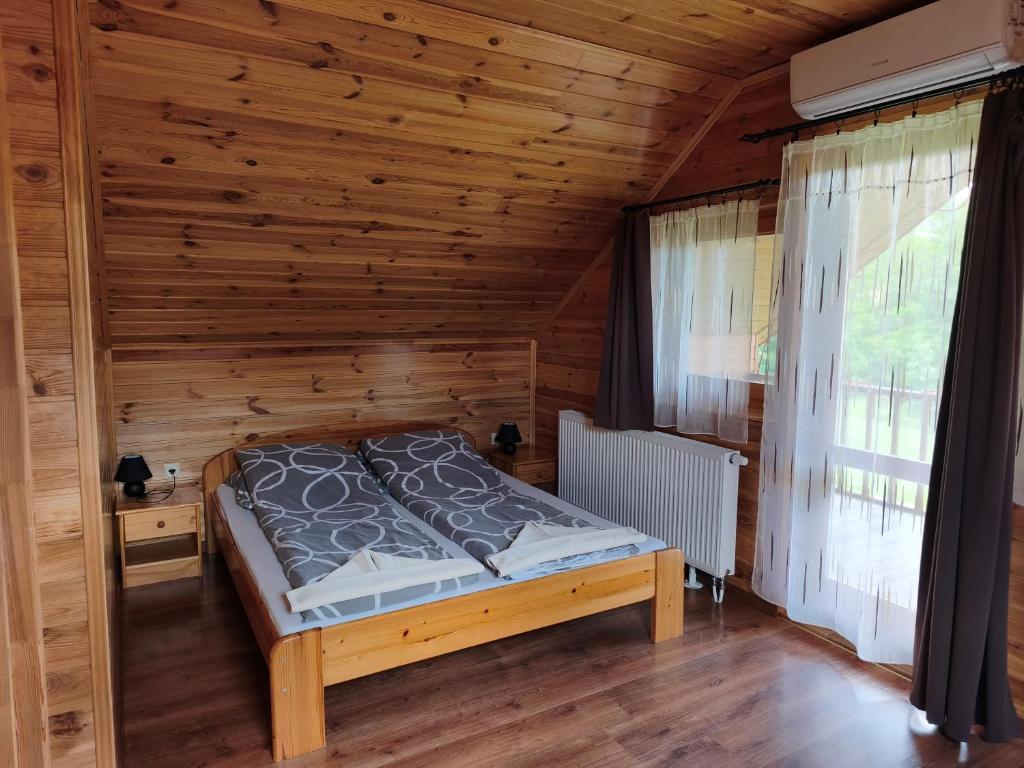 a bedroom with a bed in a wooden room at Vili Vendégház in Demjén