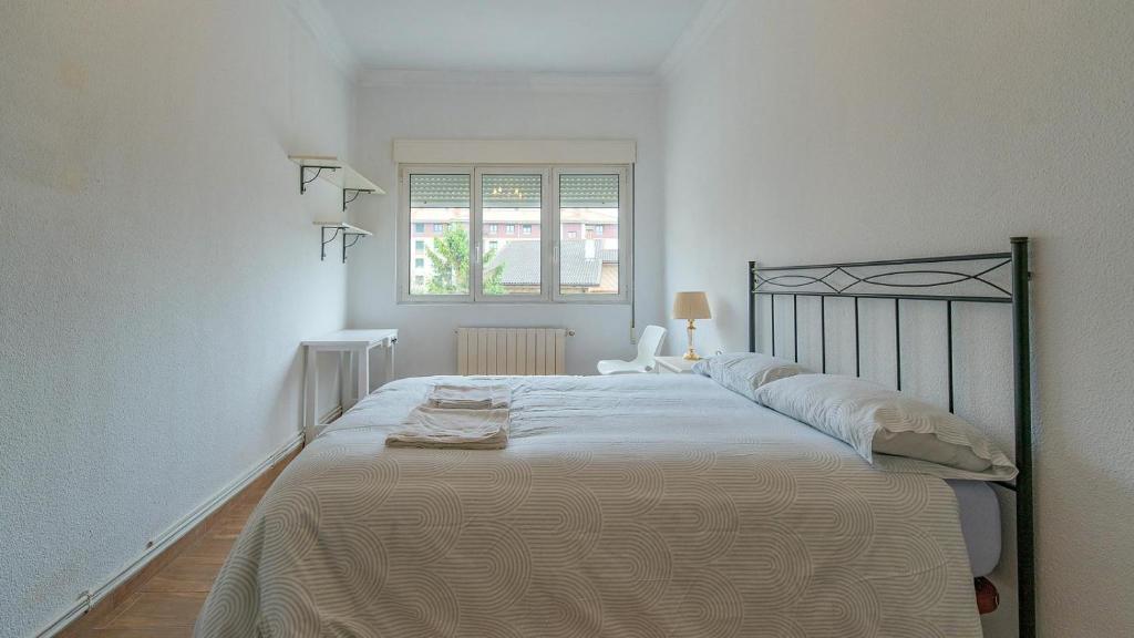 a large bed in a white room with a window at Monte la Torre in Santander