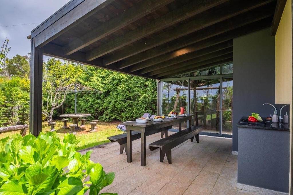 an outdoor patio with a table and benches at Sweet Orchard Escape - By Wehost in Porto Moniz