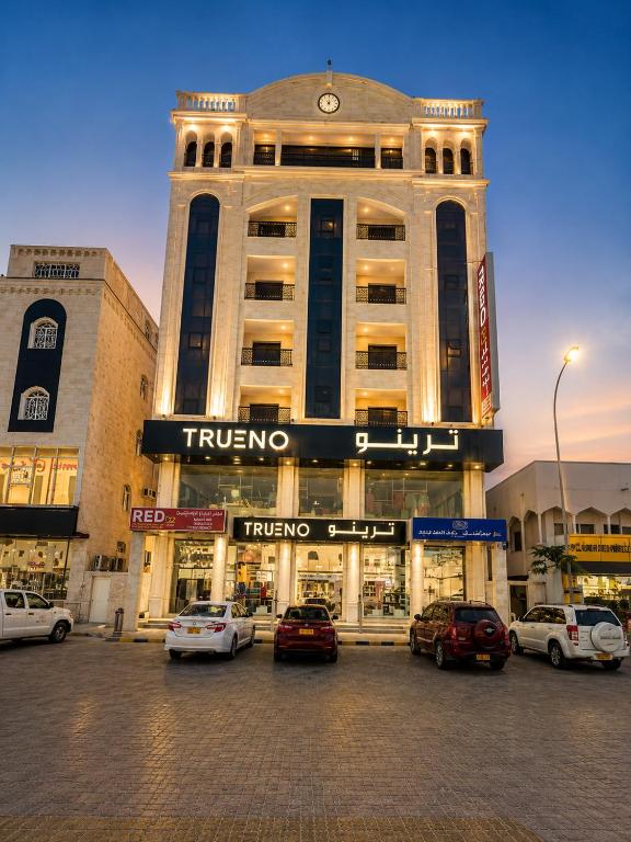 a large building with cars parked in a parking lot at hotel Alsalam suites in Salalah