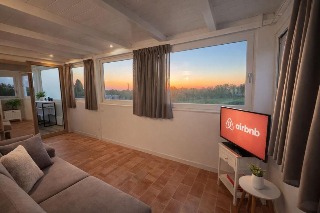 ein Wohnzimmer mit Sofa und Flachbildfernseher in der Unterkunft Lilly Rooms in Codaruina