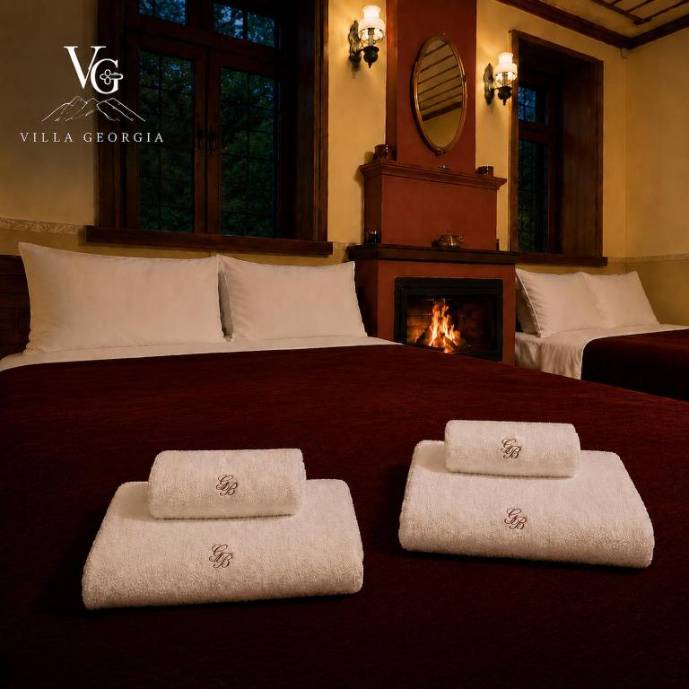 two towels on a bed with a fireplace in a bedroom at Villa Georgia in Vitsa
