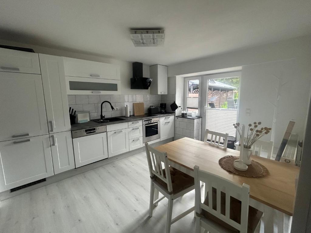 a kitchen with a wooden table and white cabinets at Kastanienidyll in Grabowhöfe