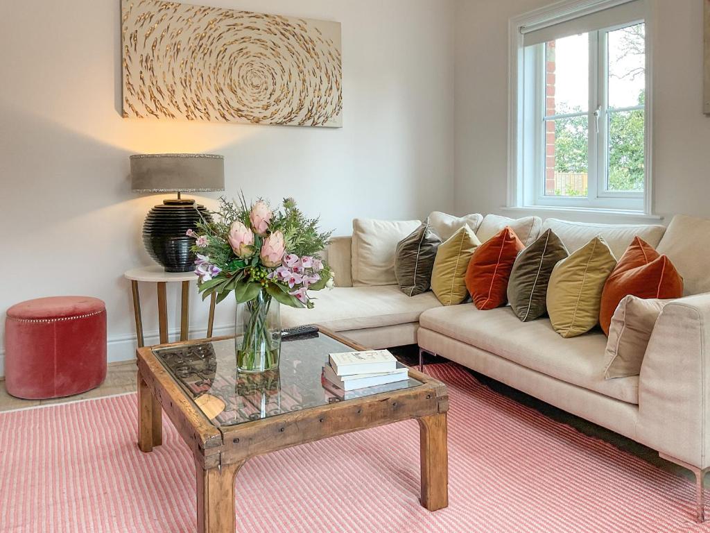 a living room with a couch and a table with a vase of flowers at Elm Tree House - Uk51762 in Landford