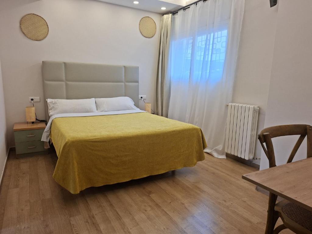 a bedroom with a bed with a yellow blanket on it at Hotel 139 in Castelldefels