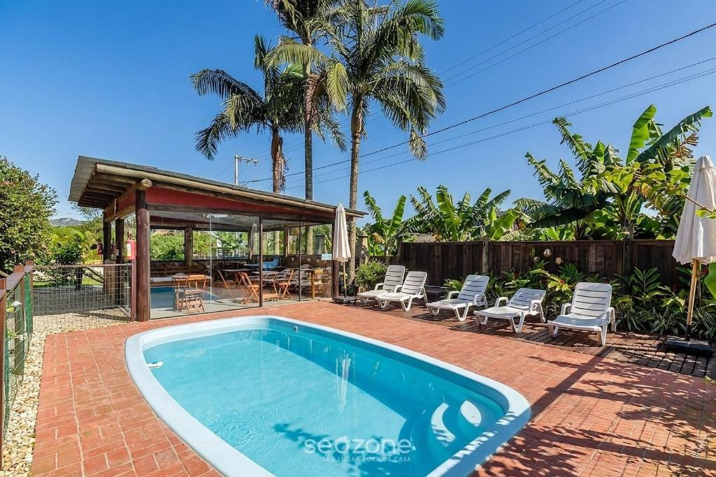 a swimming pool in a yard with chairs and a gazebo at Beautiful Pousada in the middle of nature in Bombinhas in Canto Grande