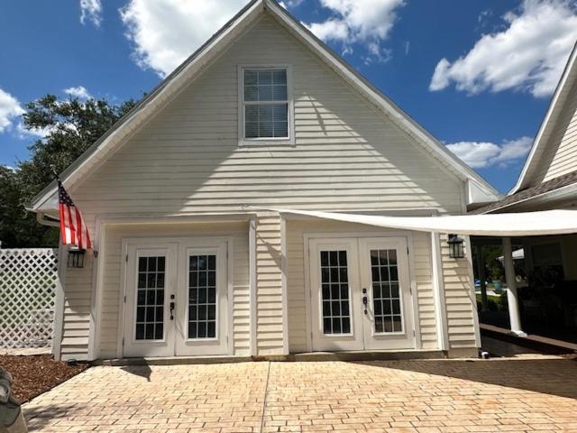 a white house with an american flag on it at Deluxe Farm Studio Apt with Pool View in Alachua