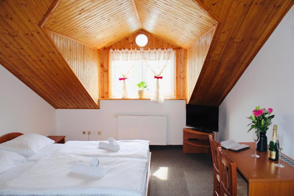 a bedroom with a bed and a desk and a television at Penzión U Tonky in Tomek