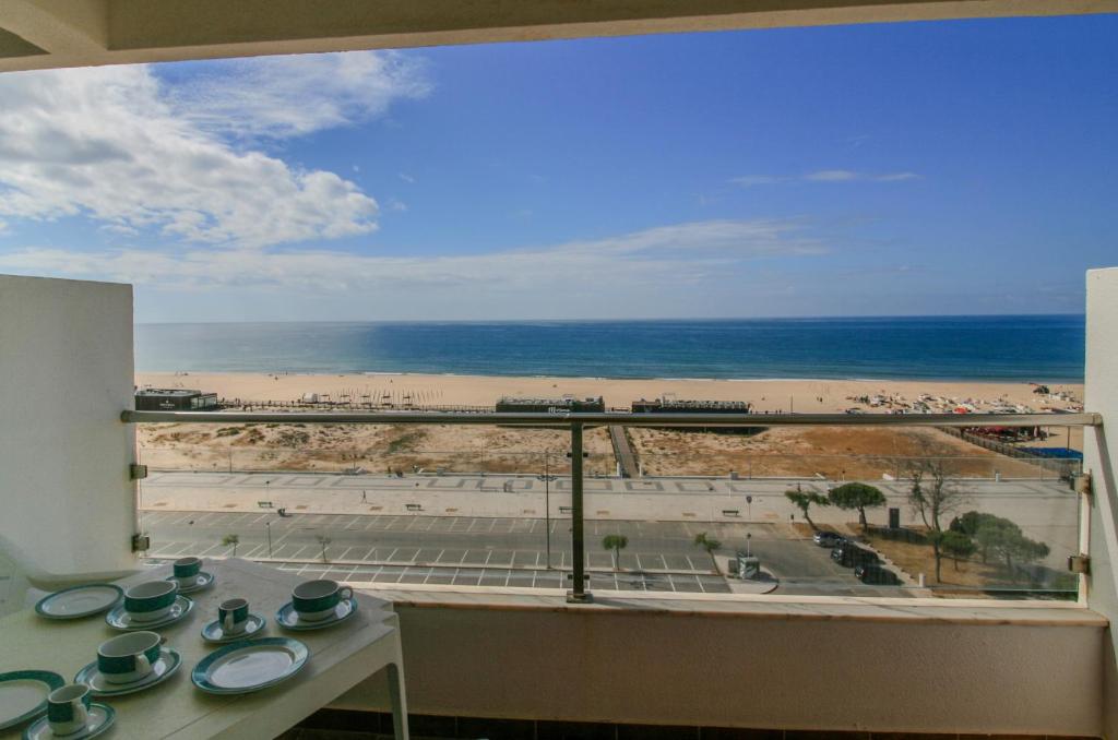 a view of the beach from a room with a table and a window at FLH Monte Gordo Balcony Flat in Monte Gordo