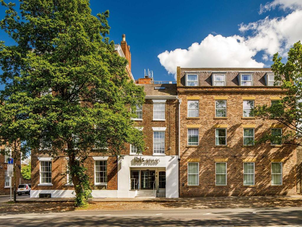 a large brick building with a tree in front of it at ibis Styles York Centre in York