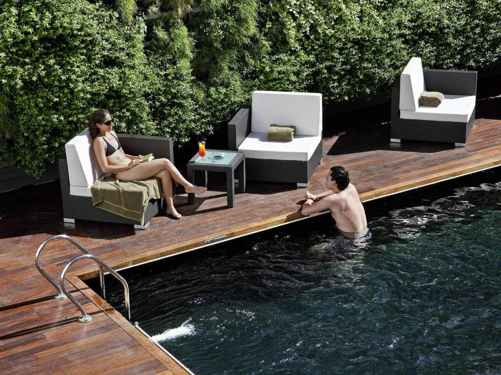 two people sitting in the water in a pool at Novotel Buenos Aires in Buenos Aires