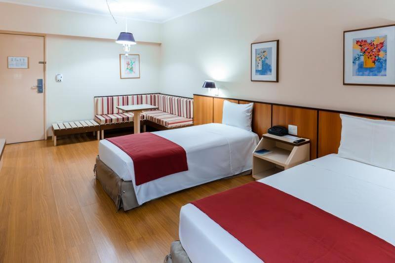 a hotel room with two beds and a table at Hotel Pan Americano in São Paulo