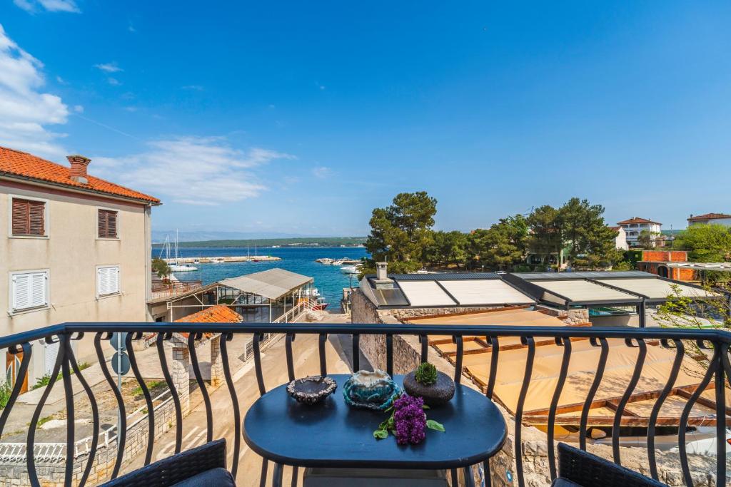 a table on a balcony with a view of the water at Apartments Celebrini in Malinska