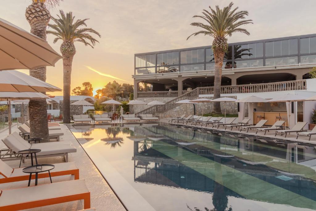 a hotel with a swimming pool with palm trees at Aldiana Club Rocca Nettuno Calabria in Tropea