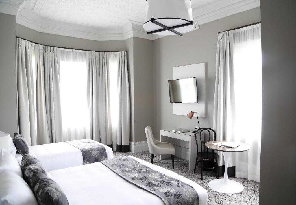 um quarto de hotel com duas camas e uma secretária em The Lurline Randwick em Sidney