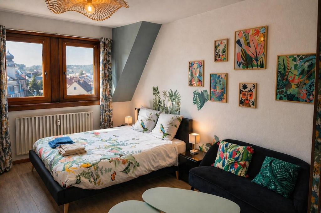a bedroom with a bed and a couch and a window at L'Atelier de Tropique in Saverne