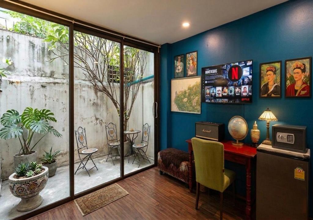 a living room with blue walls and a table and chairs at Nego Home Ancient Inn in Bangkok