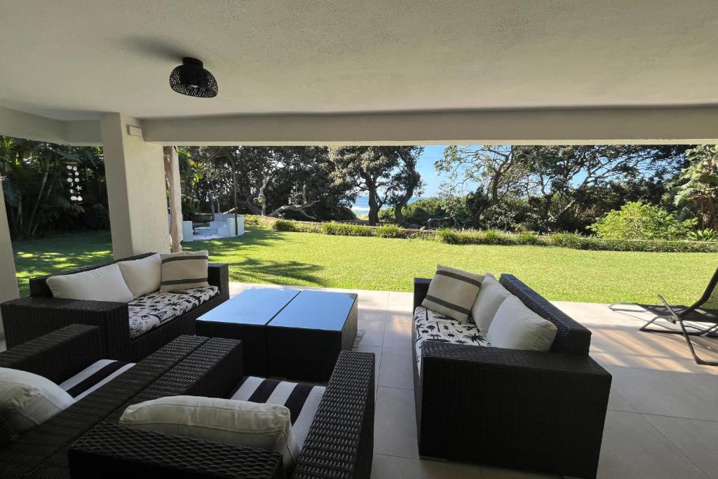 a patio with couches and a table and a lawn at SeaWaves Beach House, Shelly Beach in Shelly Beach