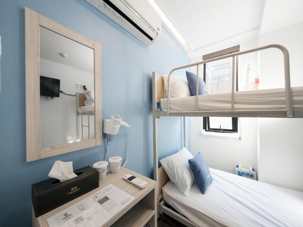 a bedroom with a bunk bed and a desk with a mirror at Sunny Guesthouse Seoul City in Seoul
