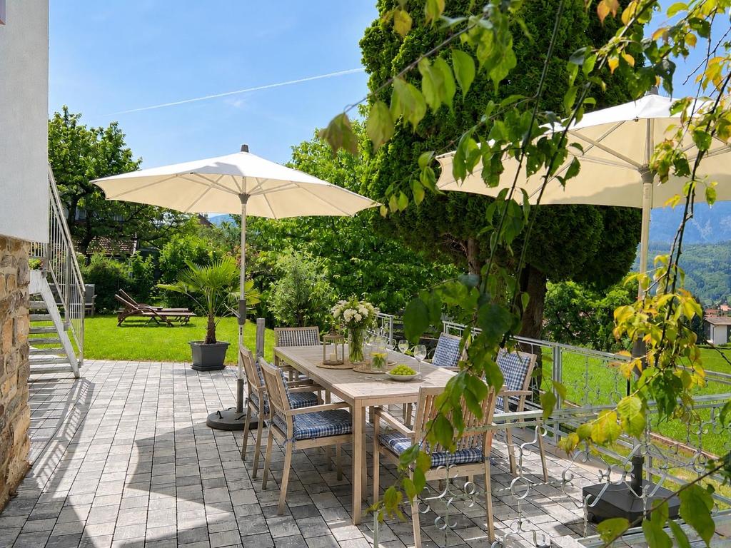 a table and chairs with an umbrella on a patio at EulenNest - Ferienhaus in Seeboden am Millstätter See mit Bergblick & Sauna in Seeboden