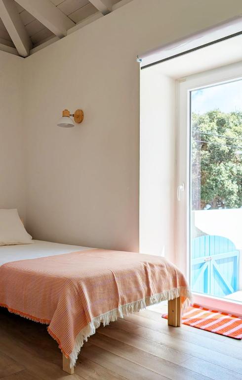 a bedroom with a bed and a large window at OKTO Beach House in Praia do Almoxarife