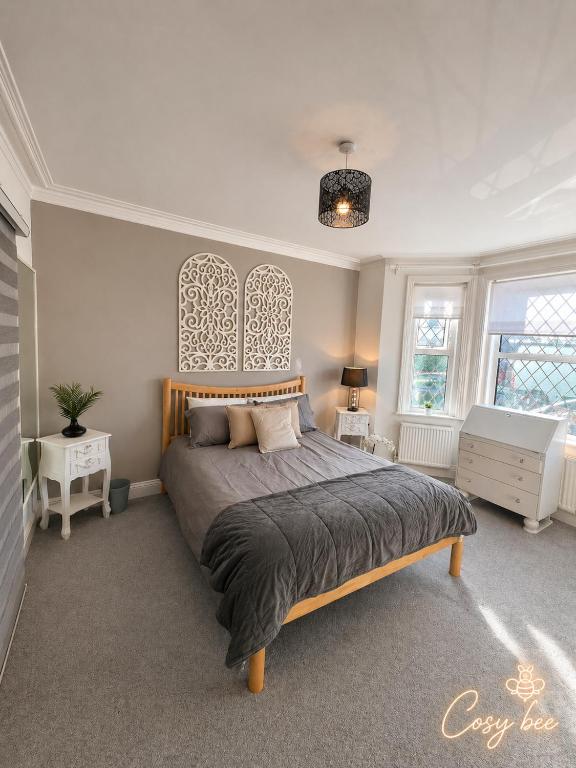 a bedroom with a large bed and two windows at Cosy Bee in Bournemouth