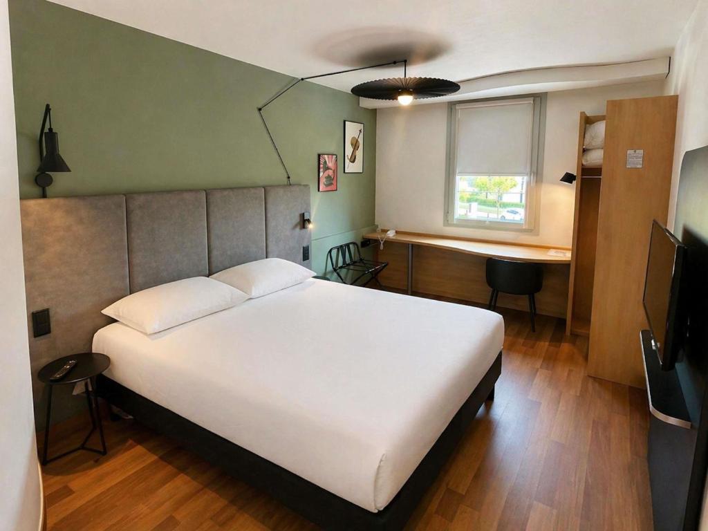 a bedroom with a large white bed and a desk at ibis Beauvais Aéroport in Beauvais