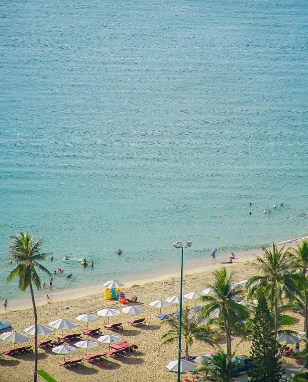 a beach with umbrellas and people in the water at The Atier Gem Suites in Nha Trang
