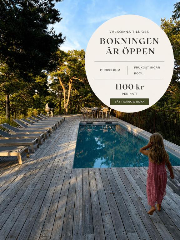 a little girl standing on a wooden deck next to a swimming pool at Villa F-GRÅ in Fårösund