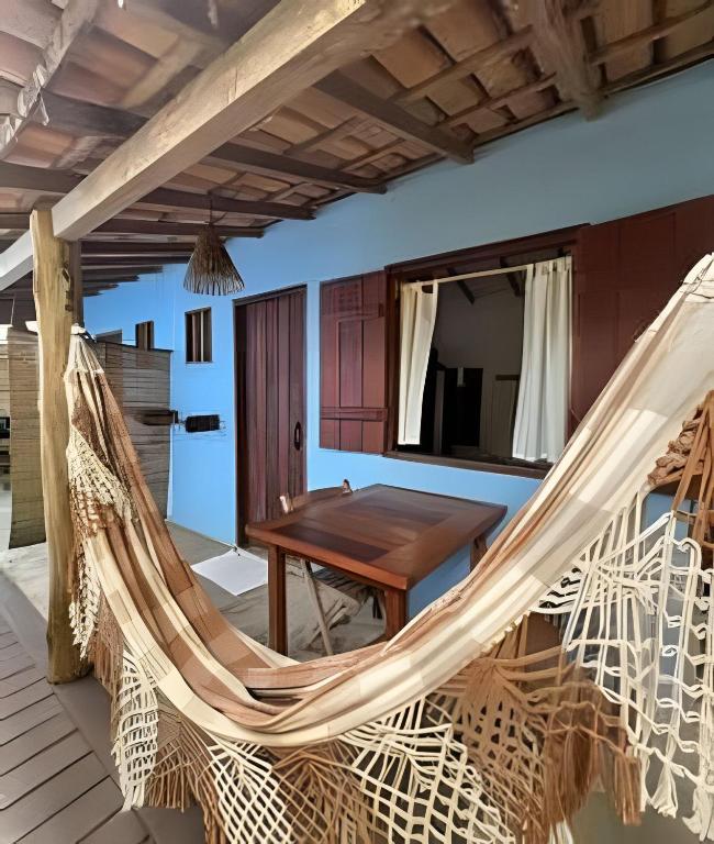 a room with a hammock and a table at Pousada Aratu - Vila de Caraíva - A apenas 100 metros da travessia de canoa in Caraíva